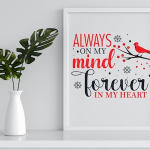 May include: A white framed print with a black and red design. The text reads "Always on my mind forever in my heart". A red cardinal bird is perched on a branch with red berries and snowflakes.