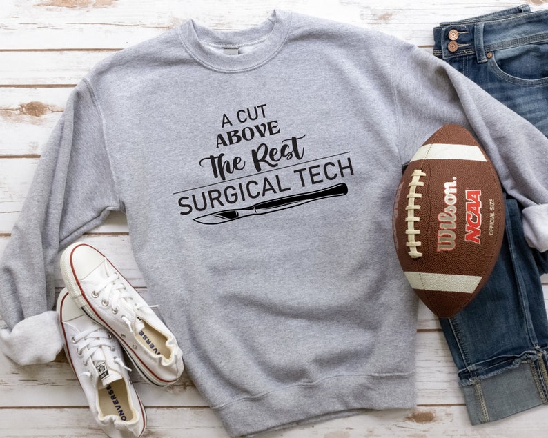 May include: A gray sweatshirt with the text "A cut above the rest surgical tech" and a black illustration of a scalpel. A football and a pair of white sneakers are also in the image.