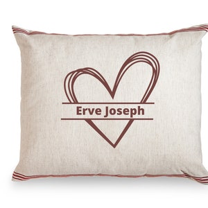 May include: A white pillow with red stripes around the edges. A brown heart with the text "Erve Joseph" inside is printed on the pillow.