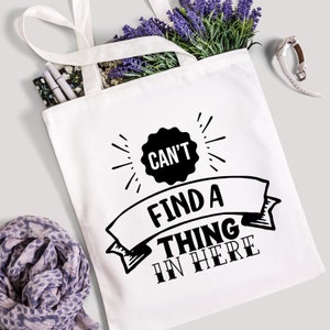 May include: White canvas tote bag with black text that reads "Can't find a thing in here".