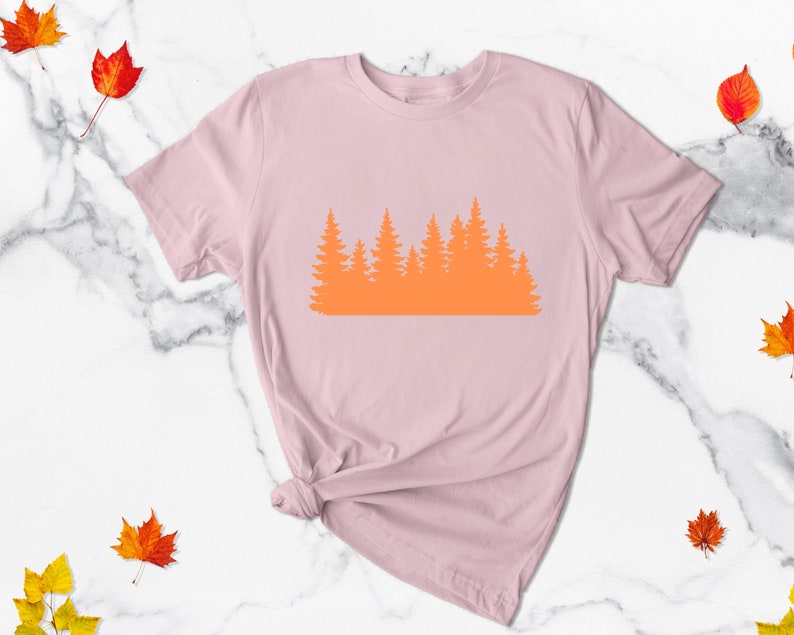 May include: A pink t-shirt with an orange silhouette of a forest on the front.