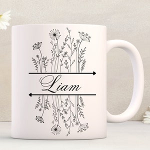 May include: White ceramic mug with a black floral design and the name "Liam" printed on the front.