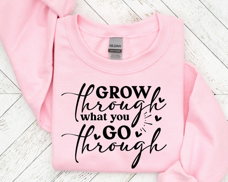 May include: Pink sweatshirt with black text that reads "GROW through what you GO through" with hearts around the text.