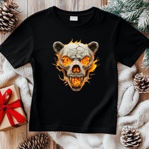 May include: Black t-shirt with a graphic of a bear skull engulfed in flames. The skull has glowing eyes and a cracked surface.