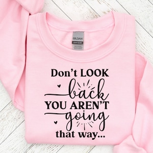 May include: Pink sweatshirt with black text that reads "Don't look back you aren't going that way..."