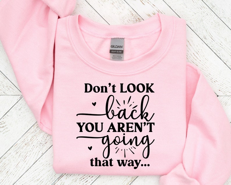May include: Pink sweatshirt with black text that reads "Don't look back you aren't going that way..."