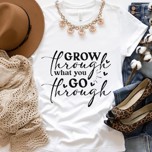 May include: White t-shirt with black text that reads "GROW through what you GO through" with small hearts around the text.