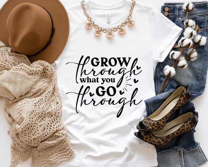 May include: White t-shirt with black text that reads "GROW through what you GO through" with small hearts around the text.