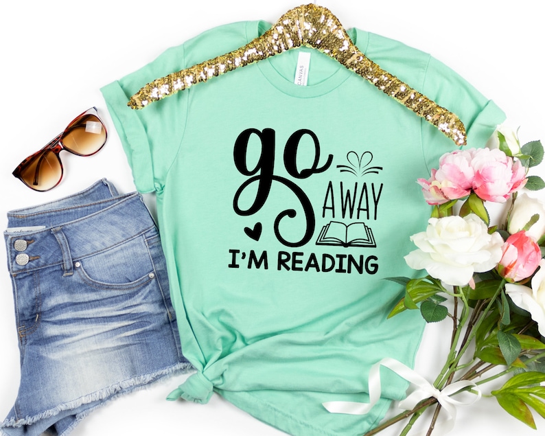 May include: A light green t-shirt with black text that reads "go away i'm reading" with a book graphic and hearts.