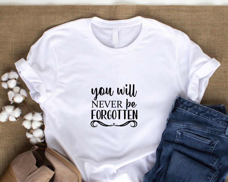 May include: White t-shirt with black text that reads "you will never be forgotten".