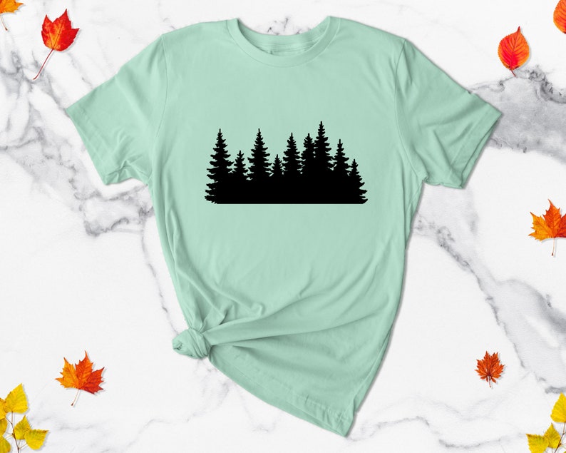 May include: A light green t-shirt with a black silhouette of a forest on the front.