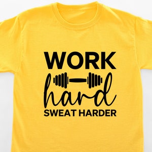 Op de afbeelding: Geel T-shirt met zwarte tekst die "WORK hard SWEAT HARDER" zegt en een zwarte halter afbeelding.