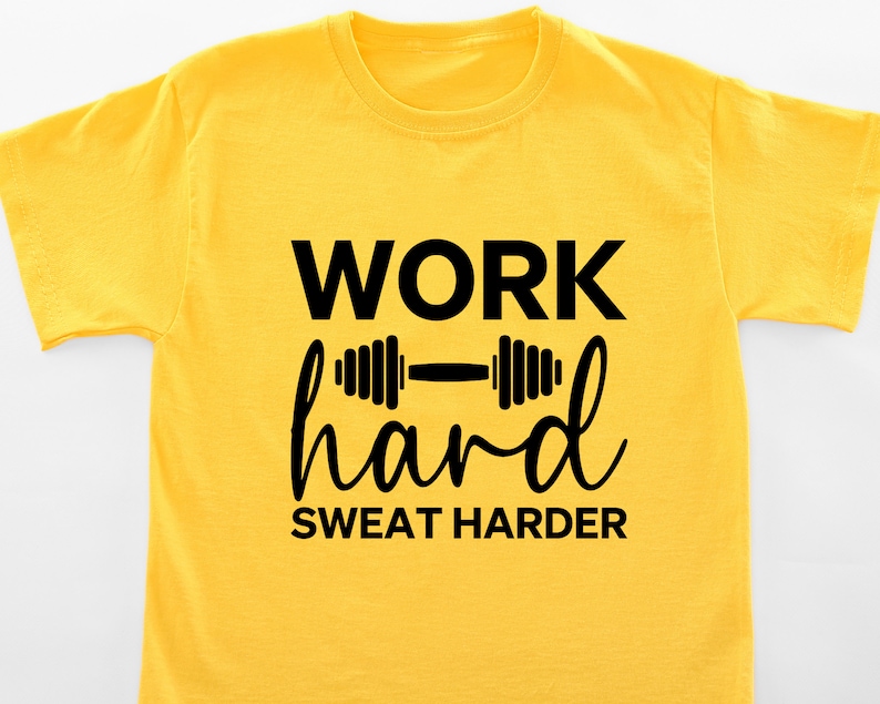 Op de afbeelding: Geel T-shirt met zwarte tekst die "WORK hard SWEAT HARDER" zegt en een zwarte halter afbeelding.