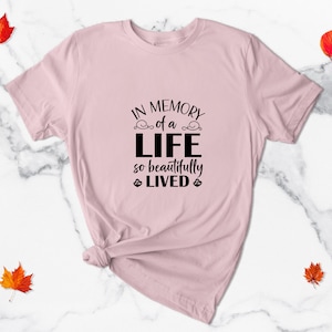 May include: A pink t-shirt with the text "In memory of a life so beautifully lived" printed in black.