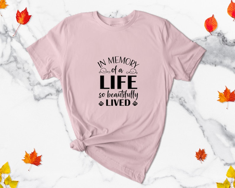May include: A pink t-shirt with the text "In memory of a life so beautifully lived" printed in black.