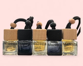 Puede incluir: Cinco pequeños frascos de vidrio con tapas de madera y tapas negras. Cada frasco tiene una cuerda negra atada a la tapa y contiene un líquido transparente. Los frascos están etiquetados con "Mazesta" y "From MD with love".