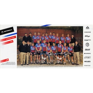 Può includere: Un gruppo di uomini con maglie da ciclismo rosso, bianco e blu si trova davanti a un muro di mattoni. Stanno tenendo le biciclette e sorridendo. La squadra è sponsorizzata da Motorola, Kellogg's, Swiss Spokes, Polar, Shimano, SRP, Wolber e Pontiac.