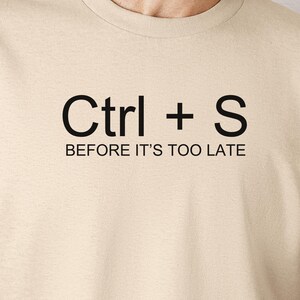 May include: A beige t-shirt with the text "Ctrl + S" and the words "Before it's too late" printed on it.