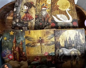 May include: A collection of six square art prints featuring whimsical illustrations. The prints depict a girl with a lantern, a fox, a swan, a castle, a dragonfly, and a unicorn, all set against a backdrop of moons and stars.