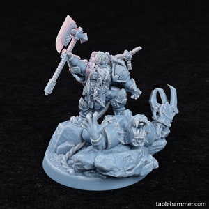 May include: A grey plastic miniature of a dwarf warrior standing over a defeated, grey plastic, monstrous creature. The dwarf is holding a large axe and is wearing armor. The creature has a large mouth and sharp claws.