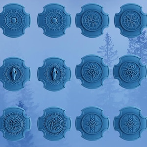 Op de afbeelding: Twaalf blauwe ronde schilden met verschillende ontwerpen, waaronder een kompas, een wolvenkop en Keltische knopen.