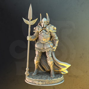 Può includere: Una statuetta in miniatura dorata di un cavaliere che indossa un'armatura e un elmo con ali. Il cavaliere tiene una lancia e sta in piedi su una base circolare con dettagli decorativi.