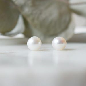 May include: A pair of white pearl stud earrings.