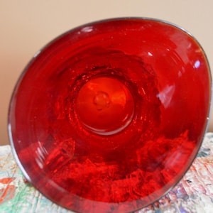 May include: A vibrant red glass bowl, viewed from above, showcasing its glossy, transparent surface. The bowl's interior reflects light, creating a captivating visual effect. The rim is smooth, and the overall design is simple yet elegant.