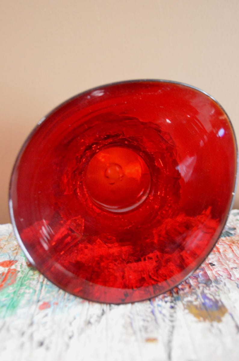May include: A vibrant red glass bowl, viewed from above, showcasing its glossy, transparent surface. The bowl's interior reflects light, creating a captivating visual effect. The rim is smooth, and the overall design is simple yet elegant.