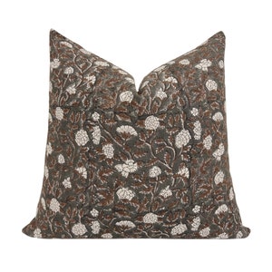 May include: A green and brown floral patterned pillow cover with white flowers.