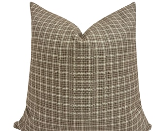 May include: A square decorative pillow with a brown and white plaid pattern. The pillow has a soft, textured appearance and is designed for home decor. The plaid design features a grid of intersecting lines.