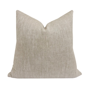 May include: A beige throw pillow with a textured fabric.