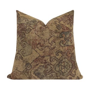 May include: A decorative throw pillow with a brown, beige, and red patterned design. The pillow has a square shape and a soft, textured fabric.