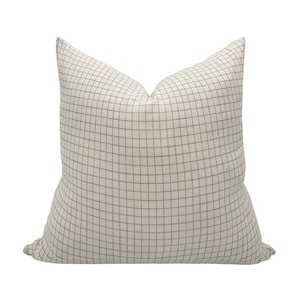 May include: A cream-colored pillow with a brown grid pattern.