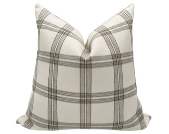 May include: A white pillow with a brown and white plaid pattern.