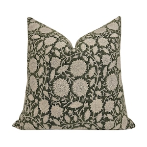 Peut inclure: Coussin carré décoratif à motif floral. Le coussin présente un fond vert foncé avec un motif répété de fleurs et de feuilles de couleur crème. Le coussin est de forme carrée et semble être fait d'un tissu doux.