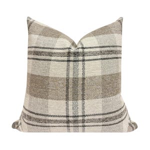May include: Square decorative pillow with a plaid pattern in neutral tones. The pillow features a woven texture with a beige, gray, and black color scheme. The pillow is designed for home decor.