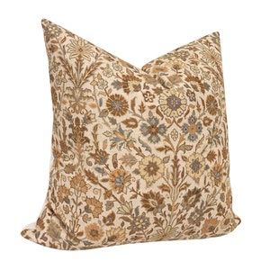 May include: A beige pillow with a brown, beige, and blue floral pattern.