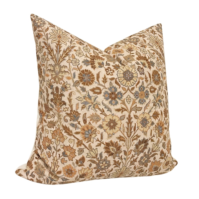May include: A beige pillow with a brown, beige, and blue floral pattern.