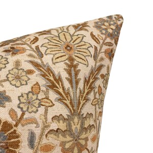 May include: A beige pillow with a floral pattern in shades of brown, beige, and blue. The pattern features intricate floral designs and leaves.