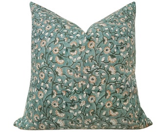 May include: A teal blue throw pillow with a floral pattern featuring white and orange flowers. The pillow is made of a soft, comfortable fabric and is perfect for adding a touch of color and style to any room.