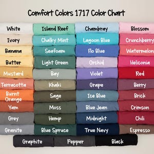 May include: A color chart titled "Comfort Colors 1717 Color Chart" displays a variety of fabric colors. The colors include white, ivory, banana, butter, mustard, terracotta, burnt orange, yam, grey, granite, graphite, island reef, chalky mint, seafoam, light green, bay, khaki, sage, moss, hemp, blue spruce, pepper, chambray, lagoon blue, flo blue, orchid, violet, grape, ice blue, blue jean, midnight, true navy, blossom, crunchberry, watermelon, heliconia, red, berry, brick, crimson, chili, espresso, and black.
