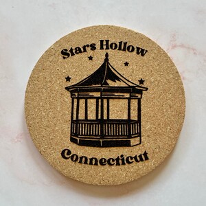 K&ouml;nnte beinhalten: Ein runder Korkuntersetzer mit einer schwarz-wei&szlig;en Illustration eines Pavillons mit dem aufgedruckten Text "Stars Hollow Connecticut".