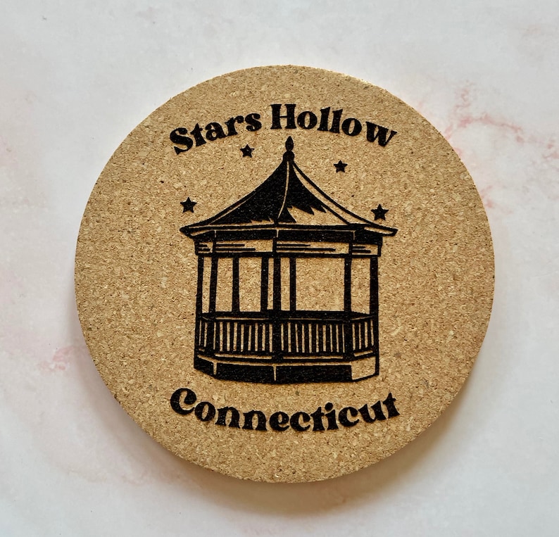K&ouml;nnte beinhalten: Ein runder Korkuntersetzer mit einer schwarz-wei&szlig;en Illustration eines Pavillons mit dem aufgedruckten Text "Stars Hollow Connecticut".