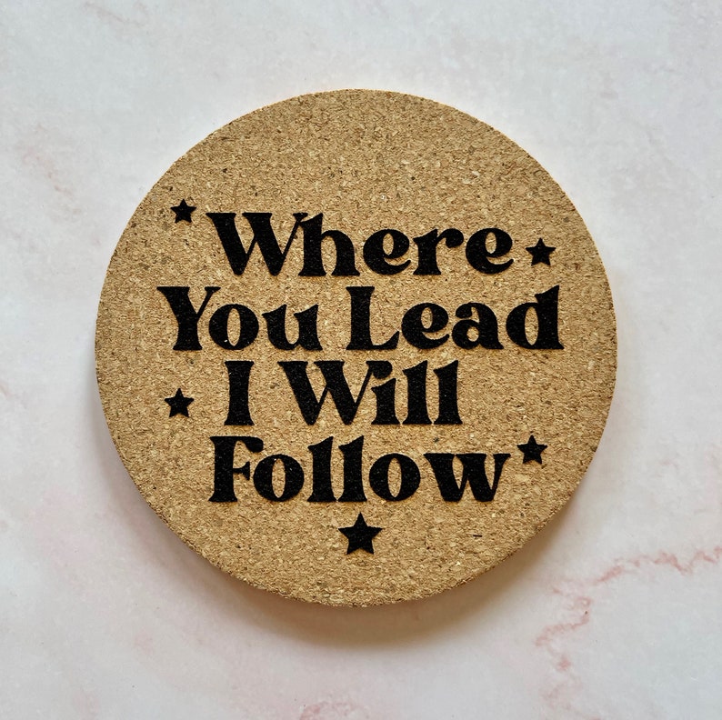 K&ouml;nnte beinhalten: Ein Korkuntersetzer mit dem Text "*Where You Lead I Will Follow*" in schwarzer Schrift.