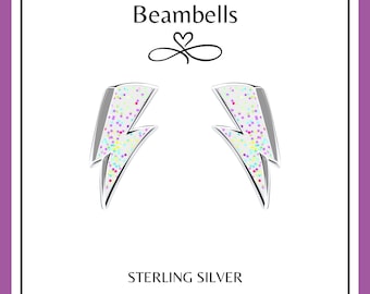 May include: A pair of sterling silver earrings shaped like lightning bolts with a white background and colorful glitter accents. Beambells is the brand name.