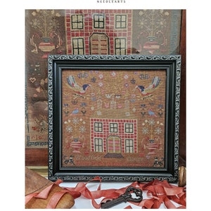 May include: A framed cross-stitch sampler with a brown background and a red house with white windows. The sampler is titled "Woodfield House" and includes the text "We God Help" and "House".