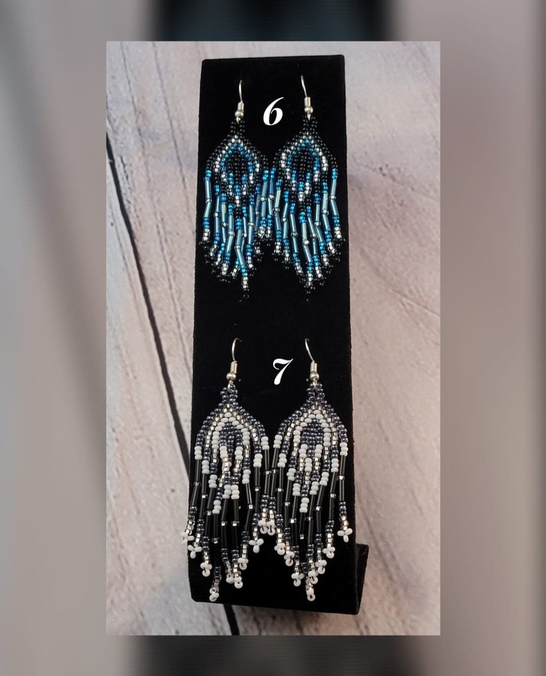 May include: Two pairs of beaded earrings, one pair is blue, black, and silver, the other pair is white, black, and silver. The earrings are labeled with the numbers 6 and 7.