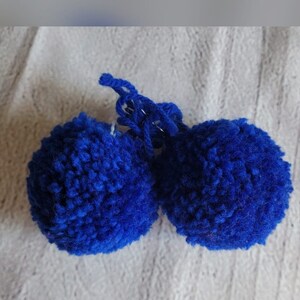 May include: Two blue fluffy pom-poms with a long strand of yarn attached to one of them.