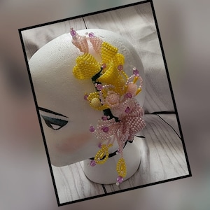 May include: A beaded flower hairpiece with pink and yellow flowers. The flowers are made of small beads and are arranged in a cascading design.
